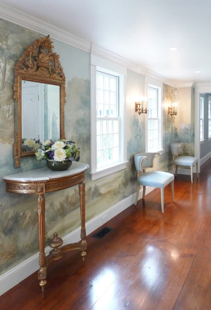 Bright foyer with antique mirror and scenic mural wallpaper