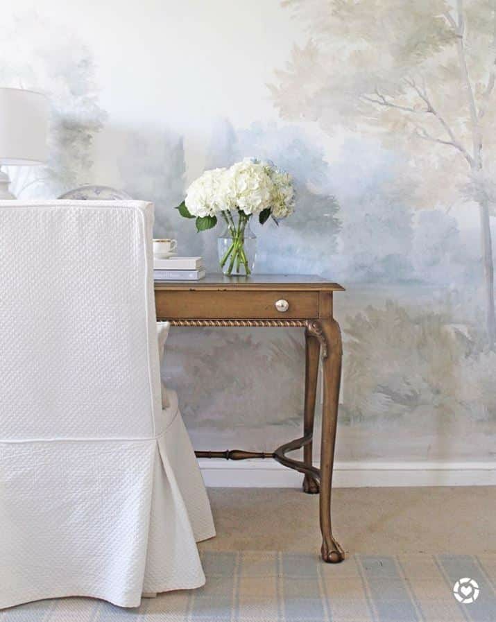 curved side table with a bouquet of elegant white flowers and blue misty landscape mural wallpaper