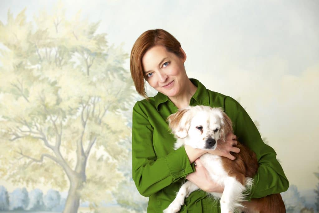 Muralist Susan Harter with her dog, Dapper, and her Rowlandson mural behind them.